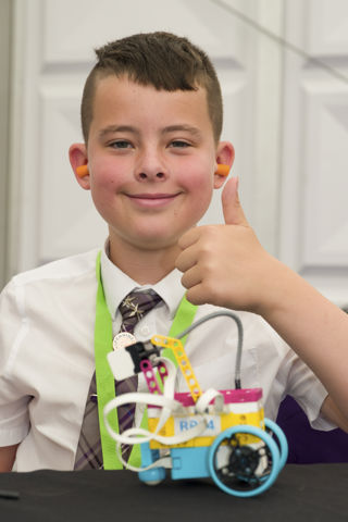 Young boy giving a thumbs up in front of a model