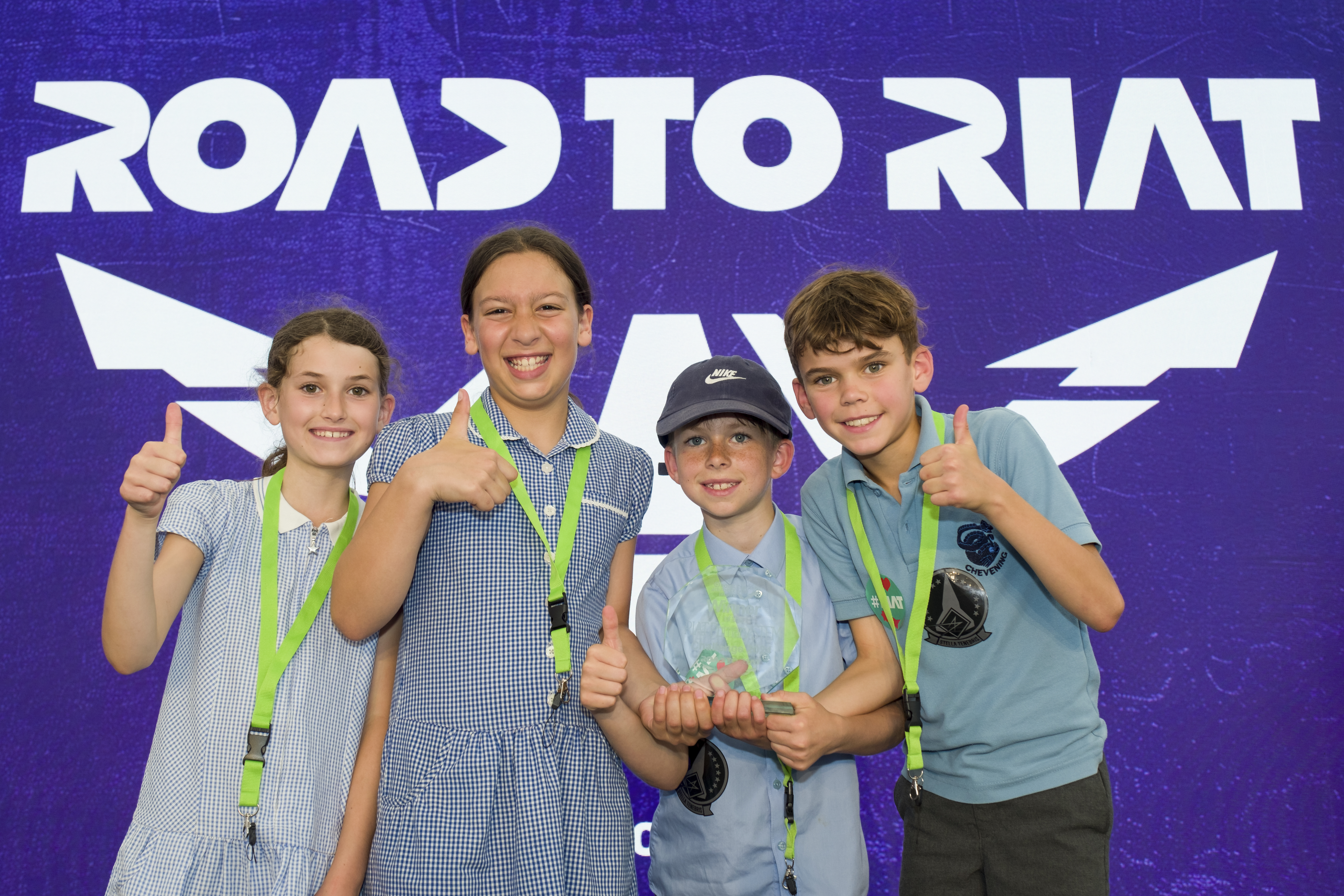 Two boy and two girl pupils standing in front of the Road to RIAT sign