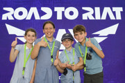 Two boy and two girl pupils standing in front of the Road to RIAT sign
