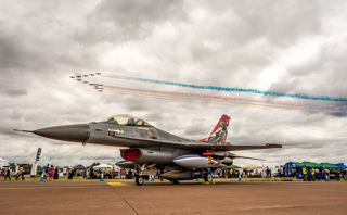 Static aircraft with flying display above it in the sky