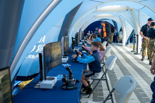 Children sitting in the RAF cadets tent in front of virtual reality screens.