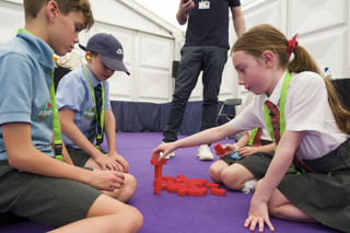 A girl and two boys in an activity with Lego bricks at Road to RIAT at RIAT24